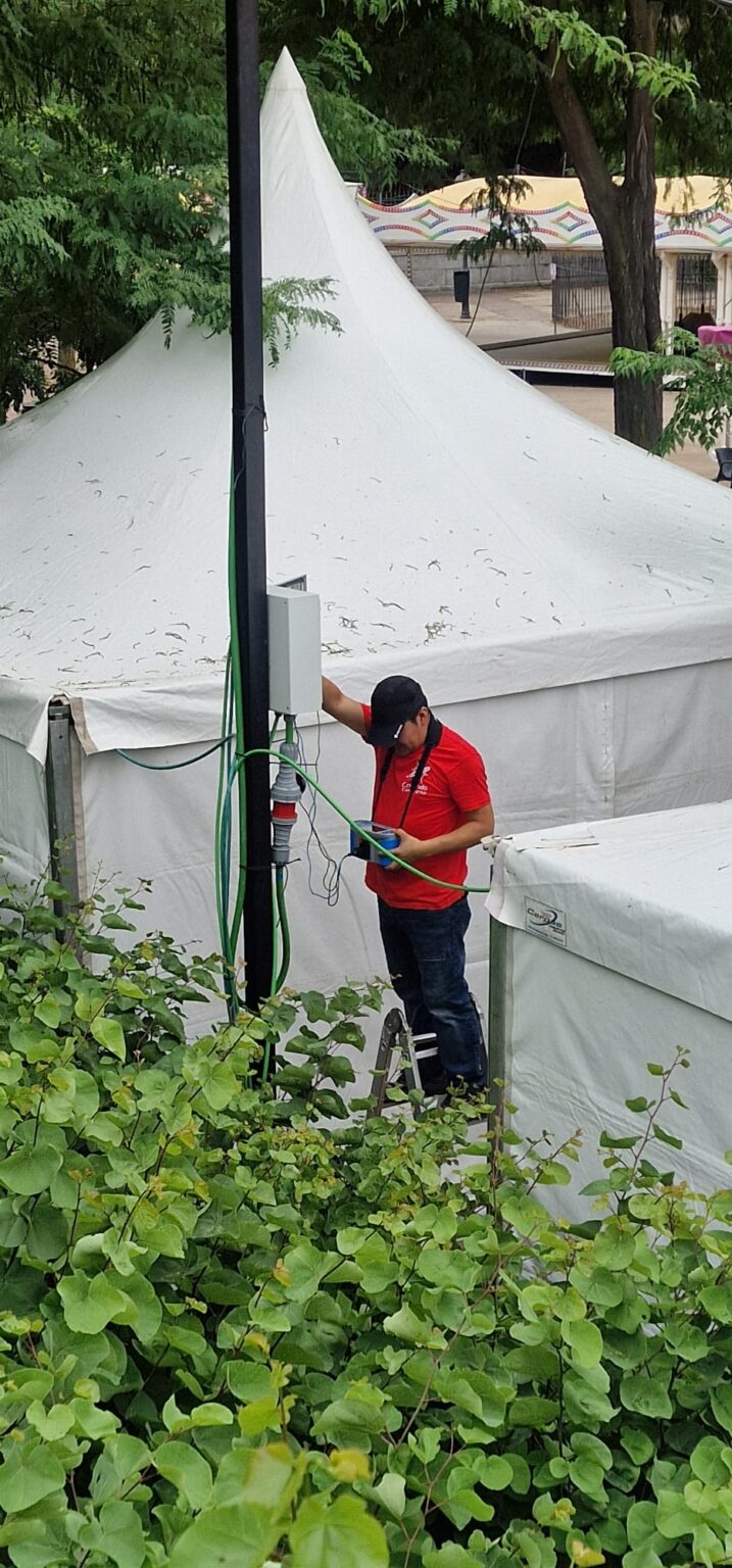 Electricista revisando un cableado o acometida eléctrica durante el desarrollo del evento.